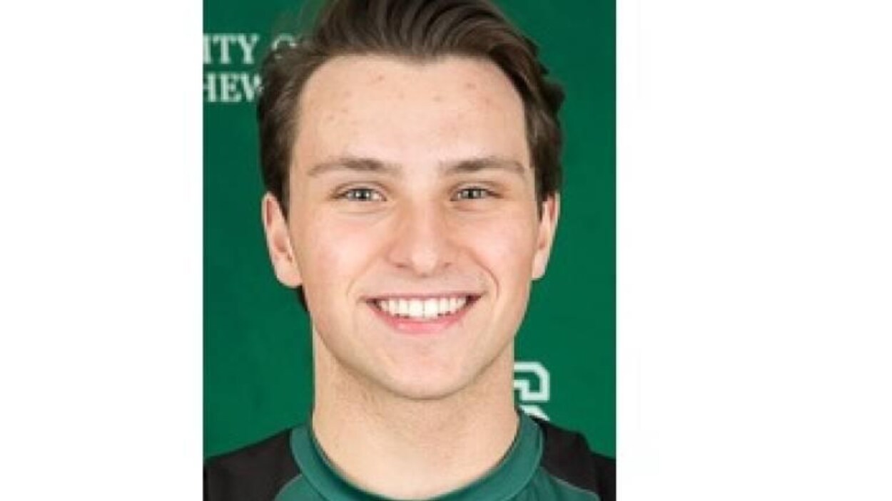 Le jeune homme porte fièrement le chandail de l'équipe de volleyball de l'Université de la Saskatchewan. Le jeune homme porte fièrement le chandail de l'équipe de volleyball de l'Université de la Saskatchewan.