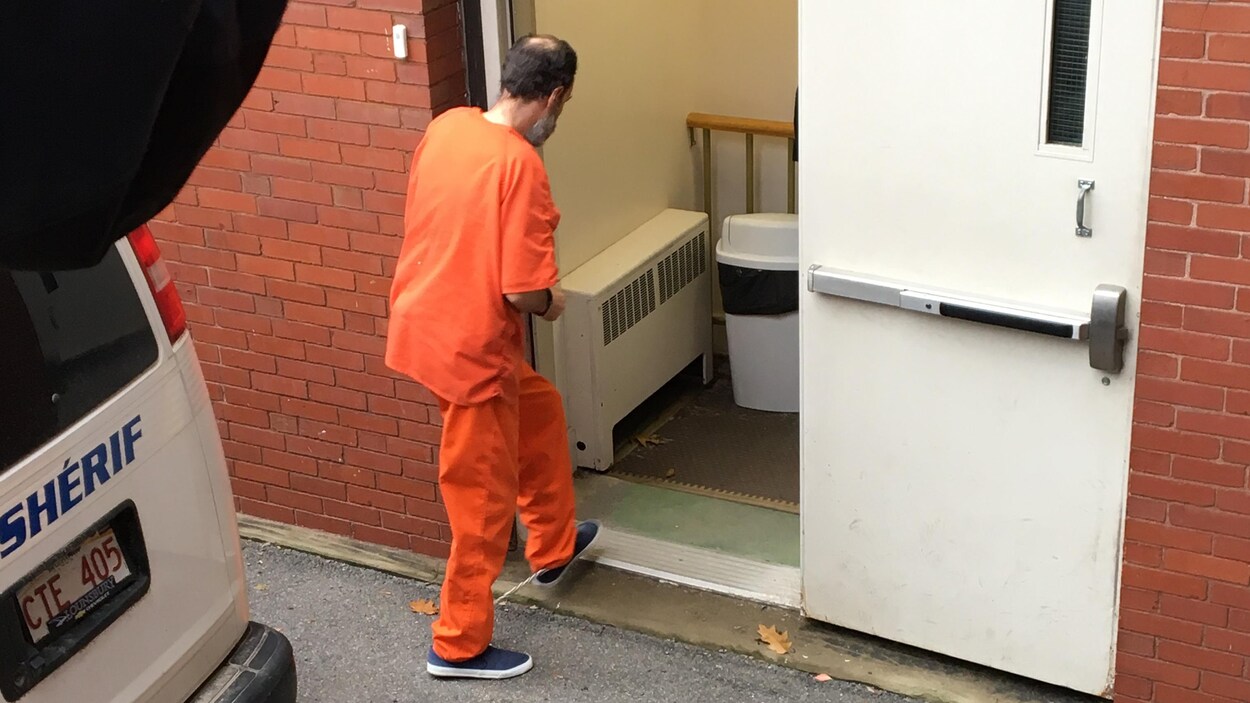 Matthew Vincent Raymond, en uniforme orange et les mains menottées.