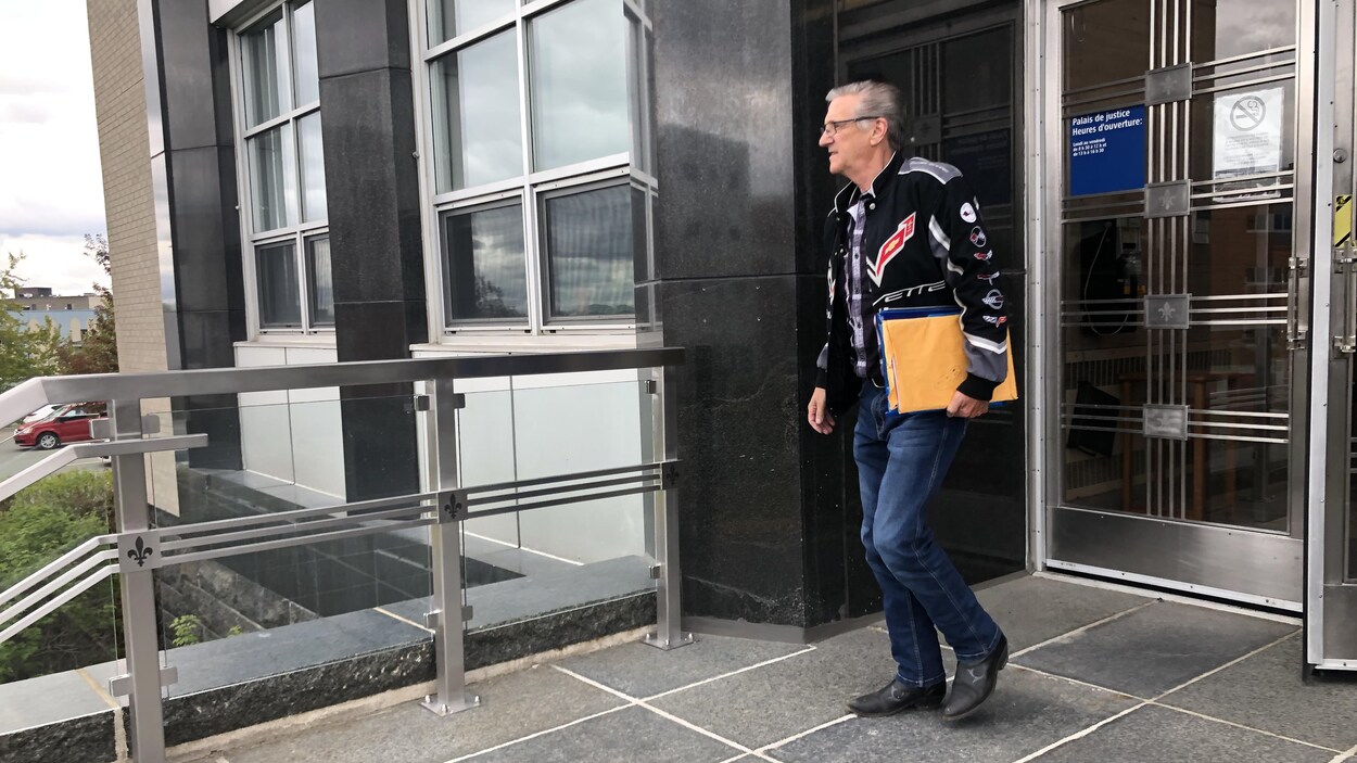 Un homme sort du palais de justice, des documents à la main.