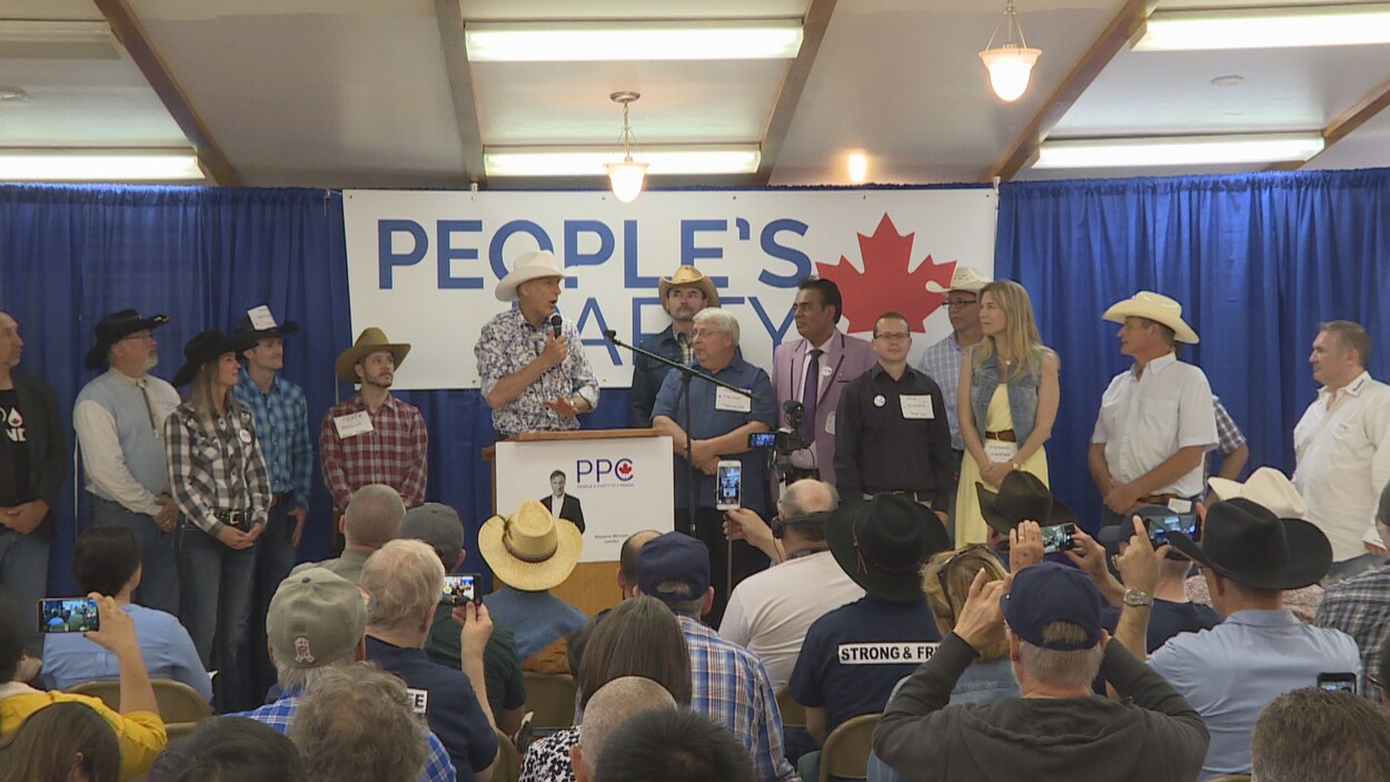 Maxime Bernier parle au podium, entouré d'une douzaine de candidats.