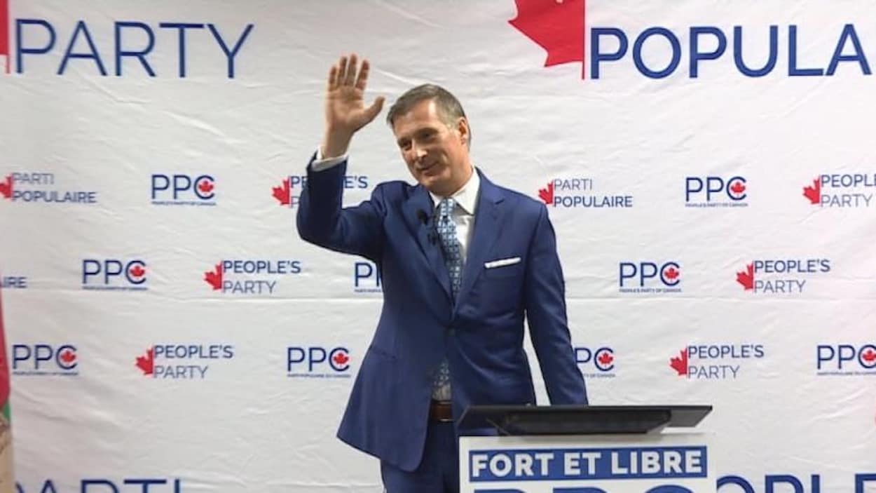 Maxime Bernier, debout sur une estrade, salue la foule.
