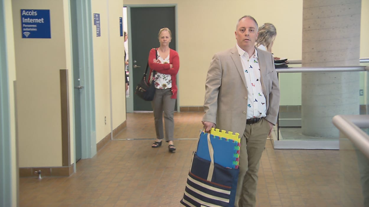 L'éducateur traîne un sac d'où dépassent les tapis colorés.