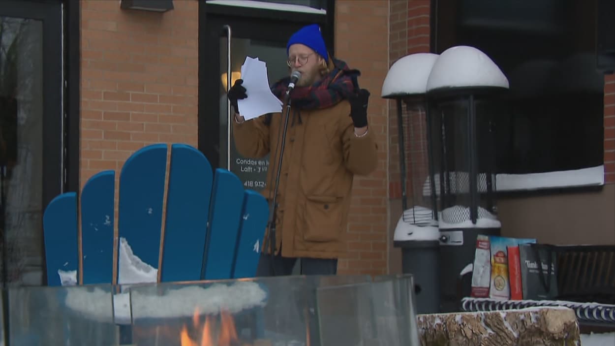 Un comédien livre un conte, feuilles à la main, sur la place publique située au coin de la rue Cartier et du boulevard René-Lévesque.