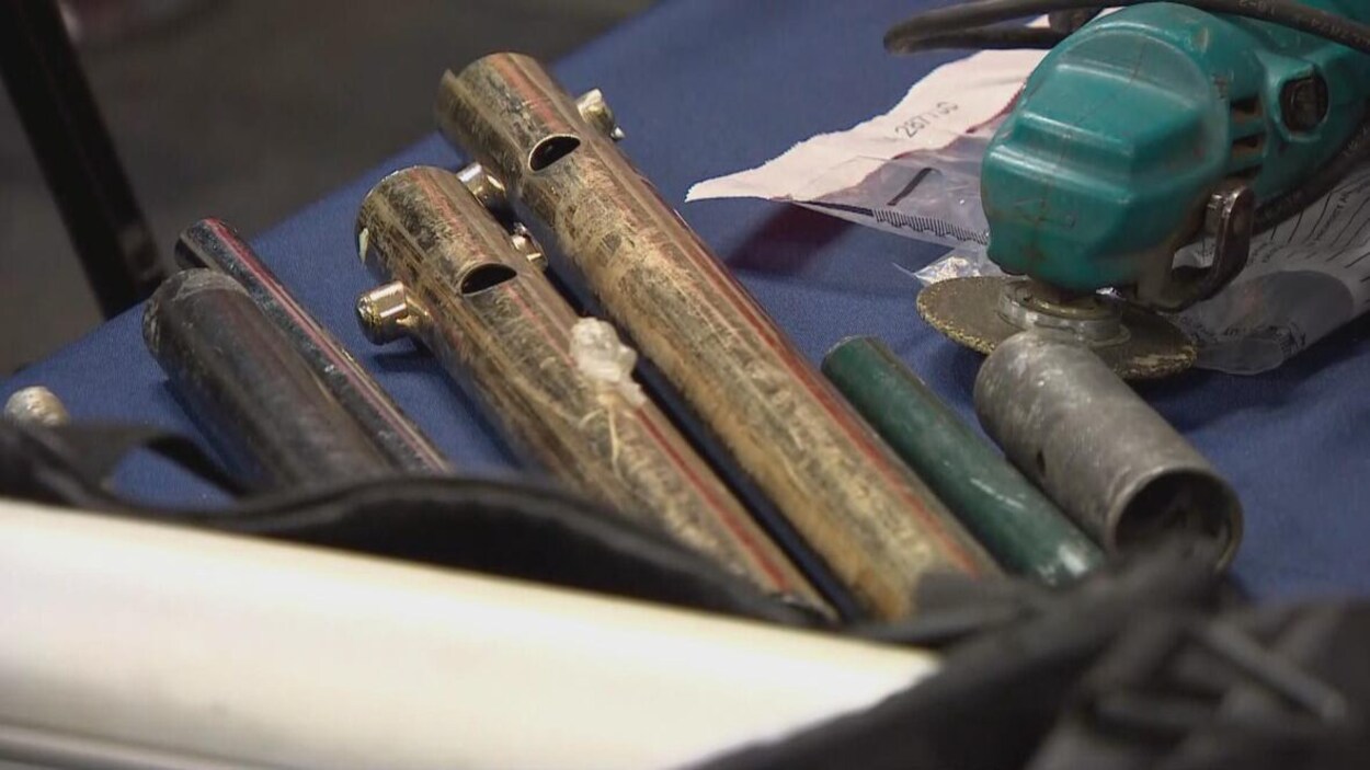 Des tuyaux, des outils et divers morceaux de ferraille sont déposés sur une table.