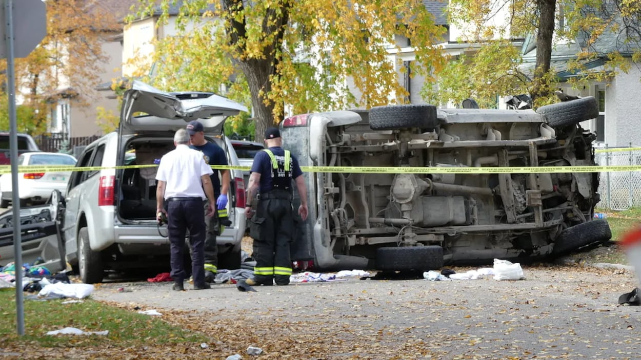 Des policiers observent un camion renversé et une camionnette endommagée dans une rue bordée par des arbres, le 26 septembre 2020.