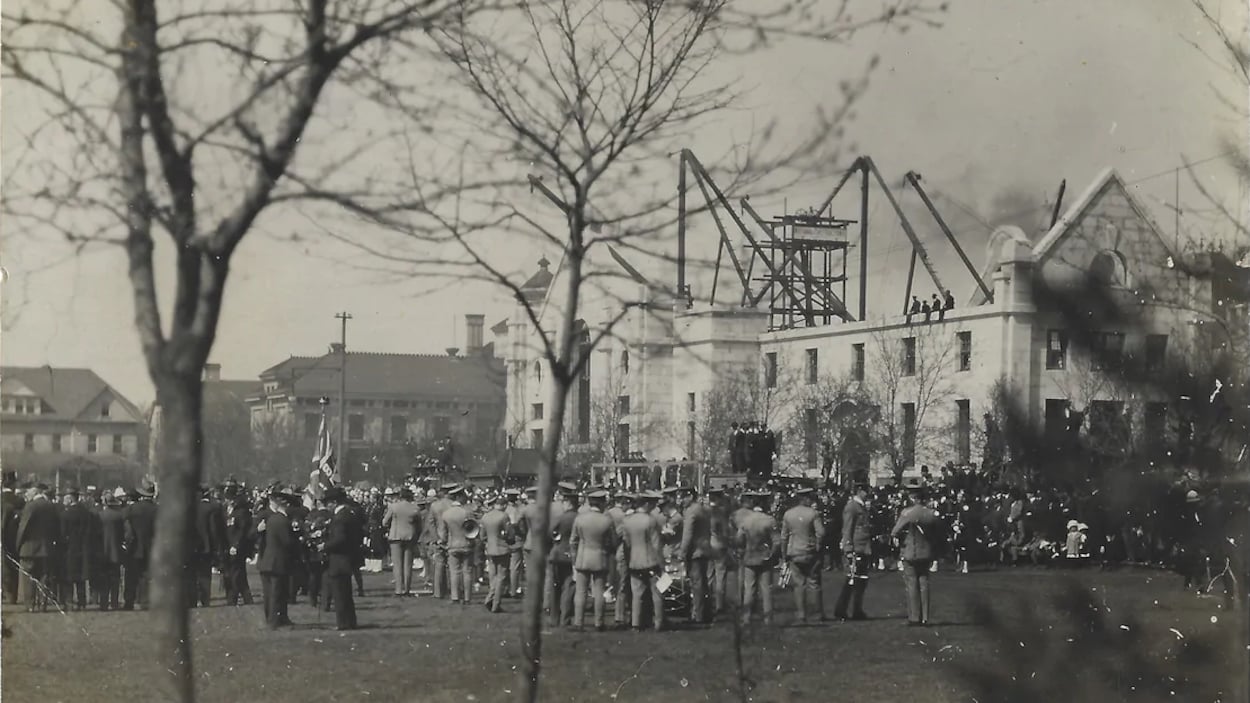 Une photo d'époque montrant des ouvriers pendant la construction d'un grand bâtiment en pierre.
