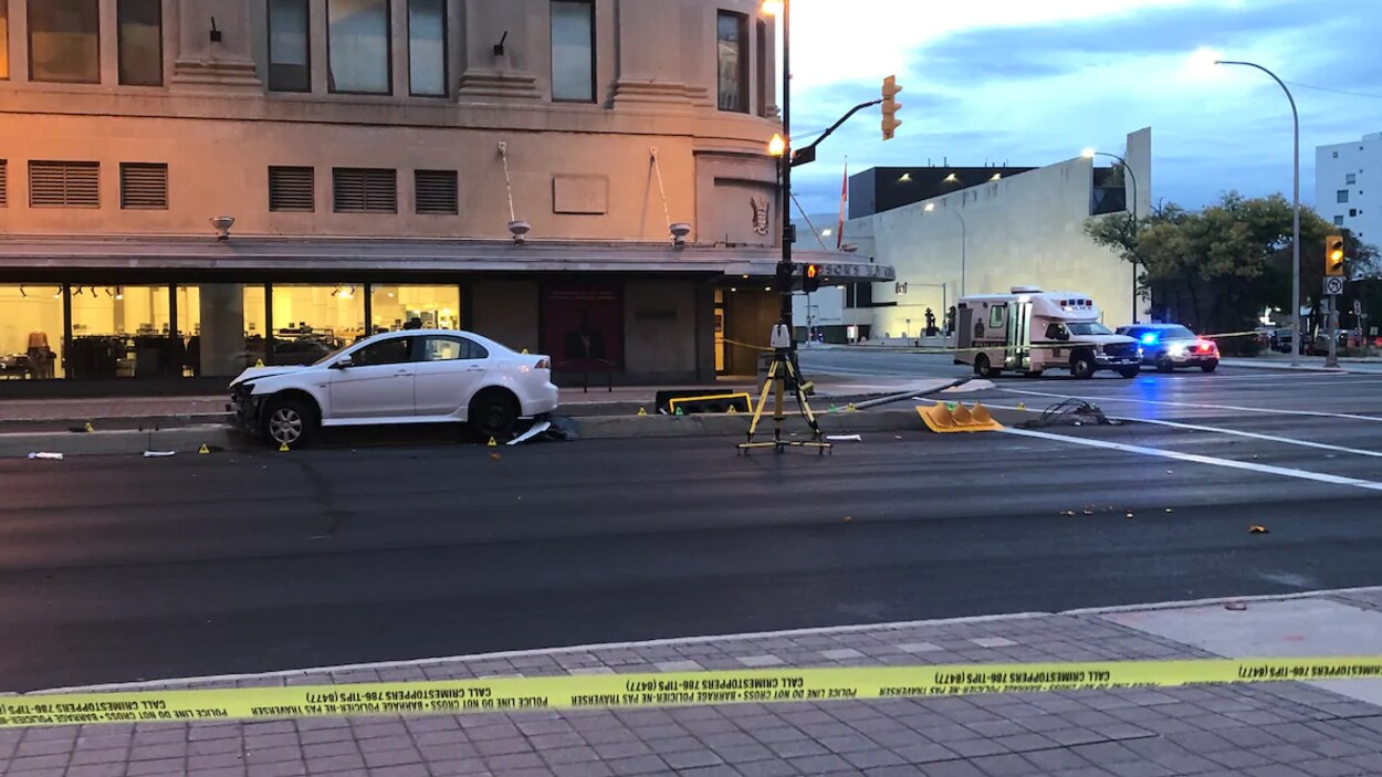 Une voiture accidentée à cheval sur un bloc de béton près d'une intersection.