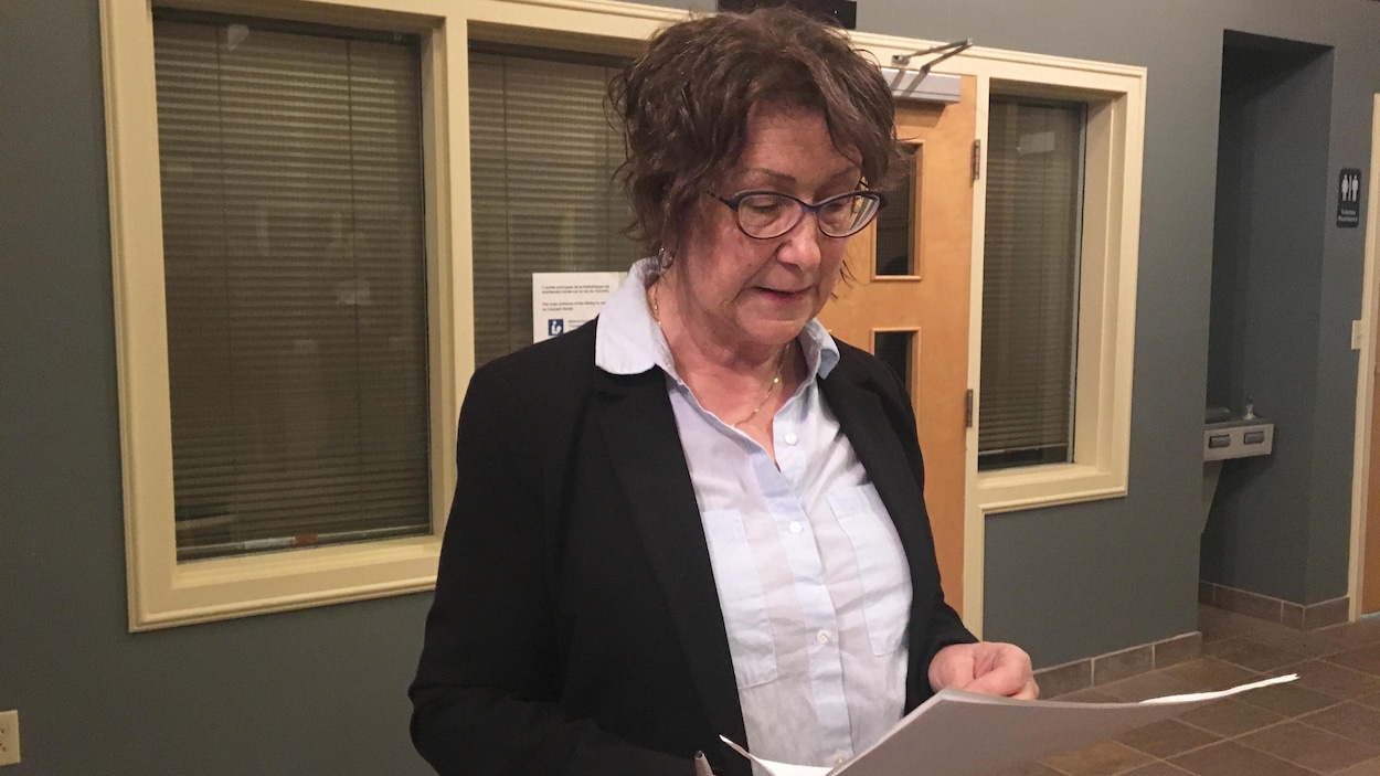Norma McGraw lit un document dans le hall de l'hôtel de ville