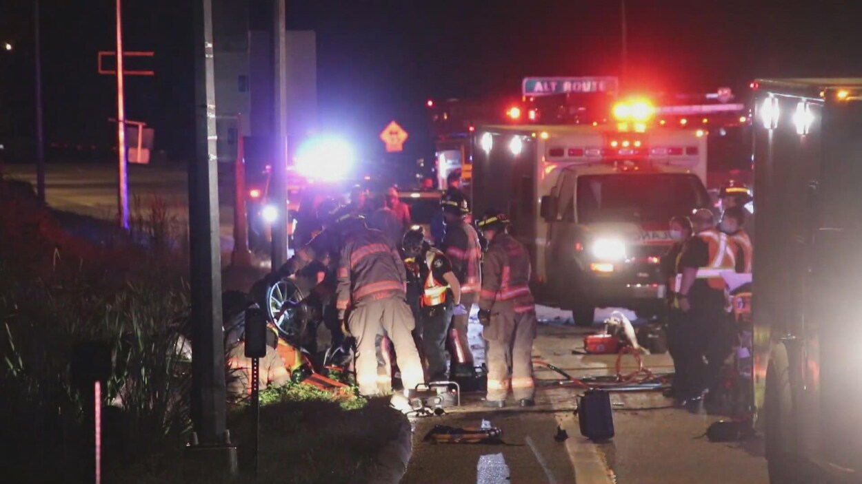Des pompiers tentent d'extirper le conducteur de la McLaren au bord de la Transcanadienne.