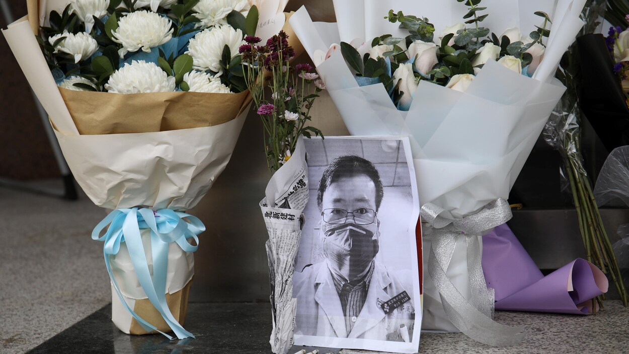 Des bouquets de fleurs près de la photo du jeune médecin sont déposés sur le sol.