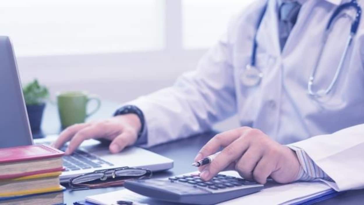 Un médecin anonyme assis devant son ordinateur Un médecin anonyme assis devant son ordinateur