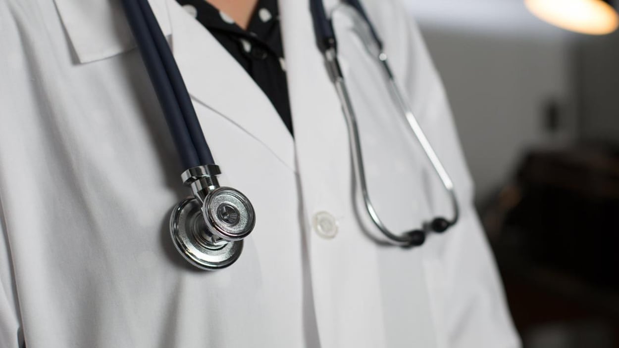 Haut de corps d'un médecin portant un sthétoscope autour de son cou.