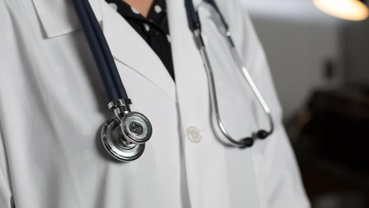 Haut de corps d'un médecin portant un sthétoscope autour de son cou.