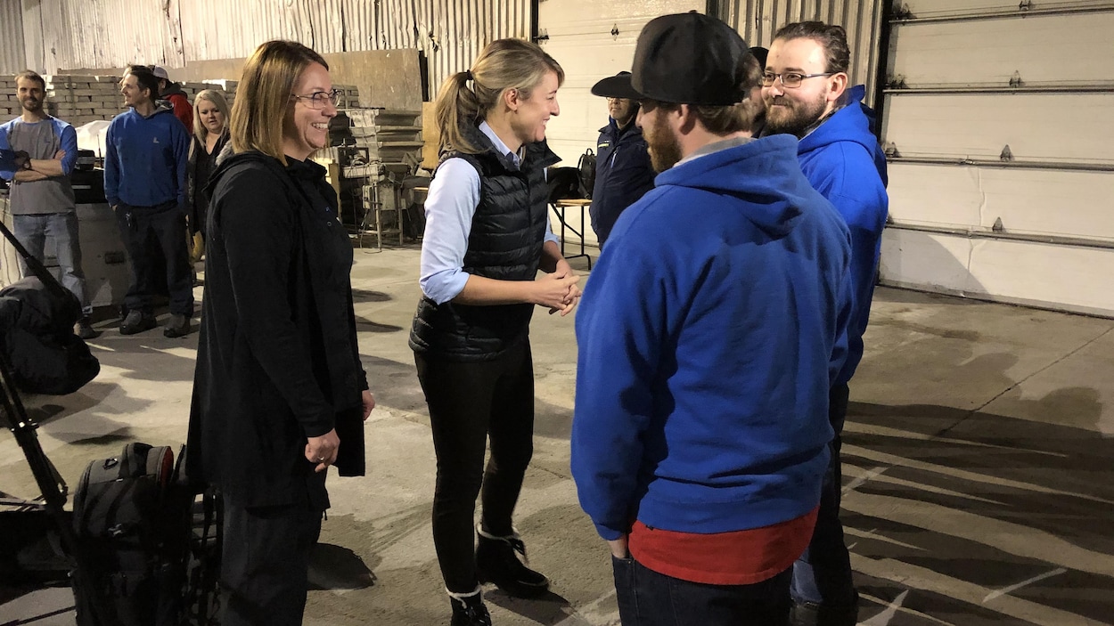 Mélanie Joly et Joanne Lefebvre saluent des travailleurs de l'usine.