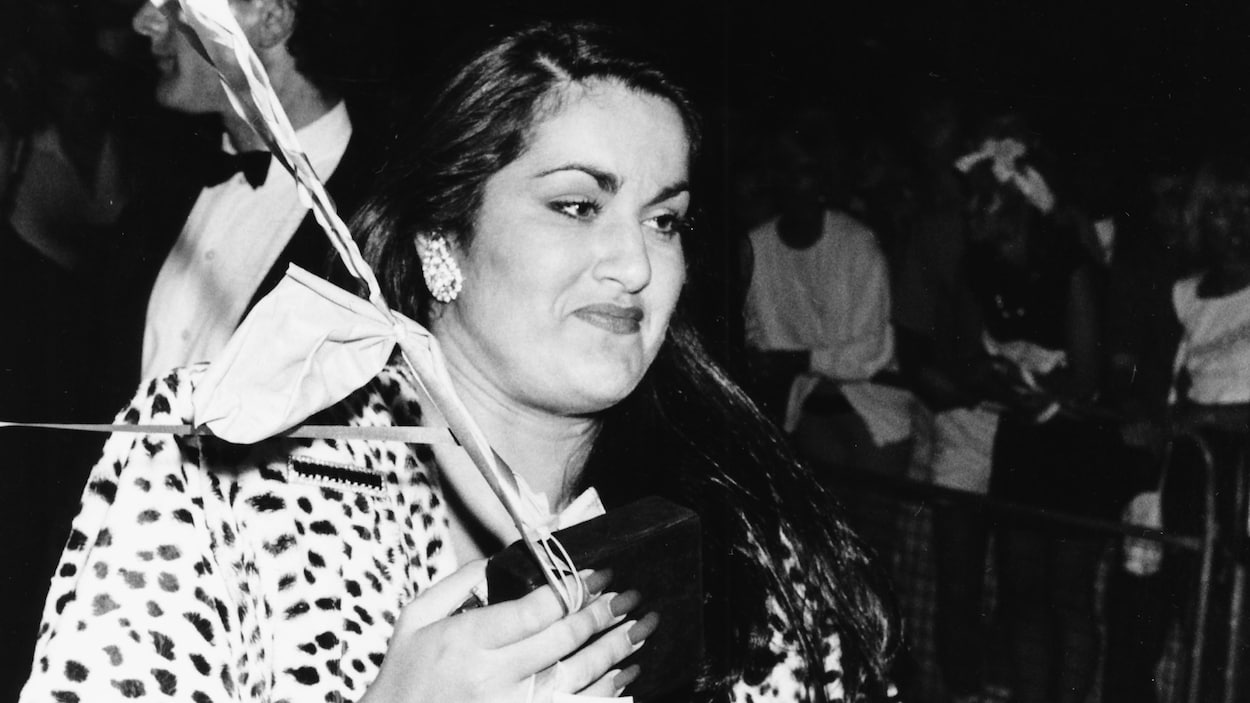 Dans une photo en noir et blanc, une femme tient un bouquet de ballons dans sa main.