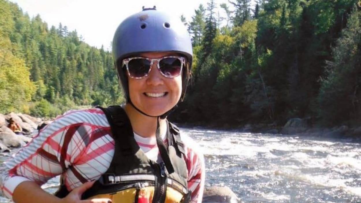 Une femme souriante devant une rivière.