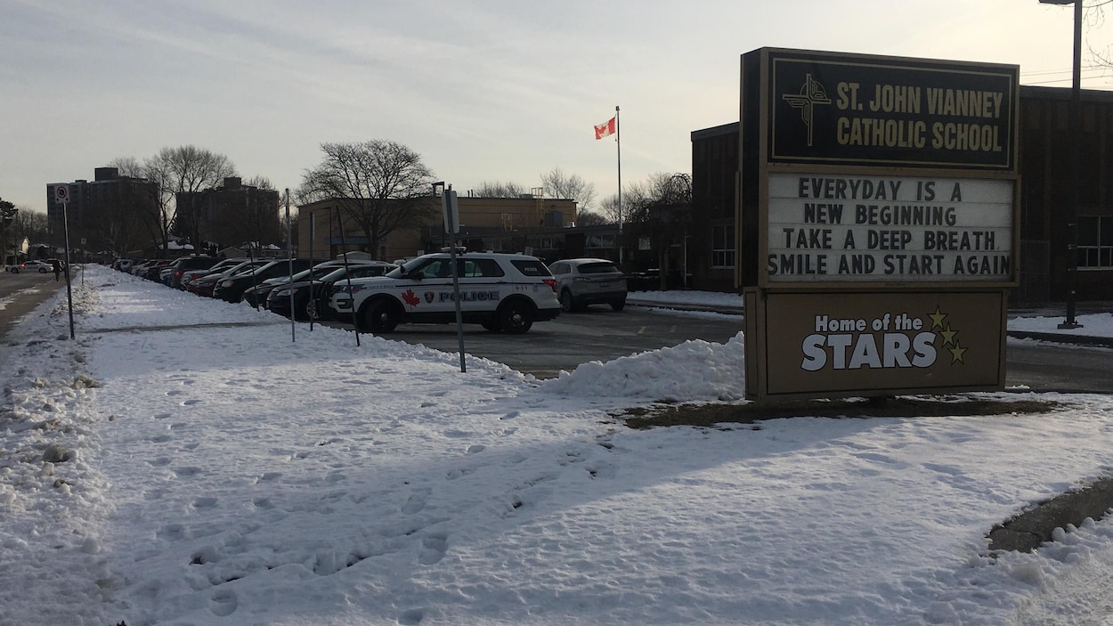 Vue extérieure d'une école. Des voitures de police sont stationnés devant