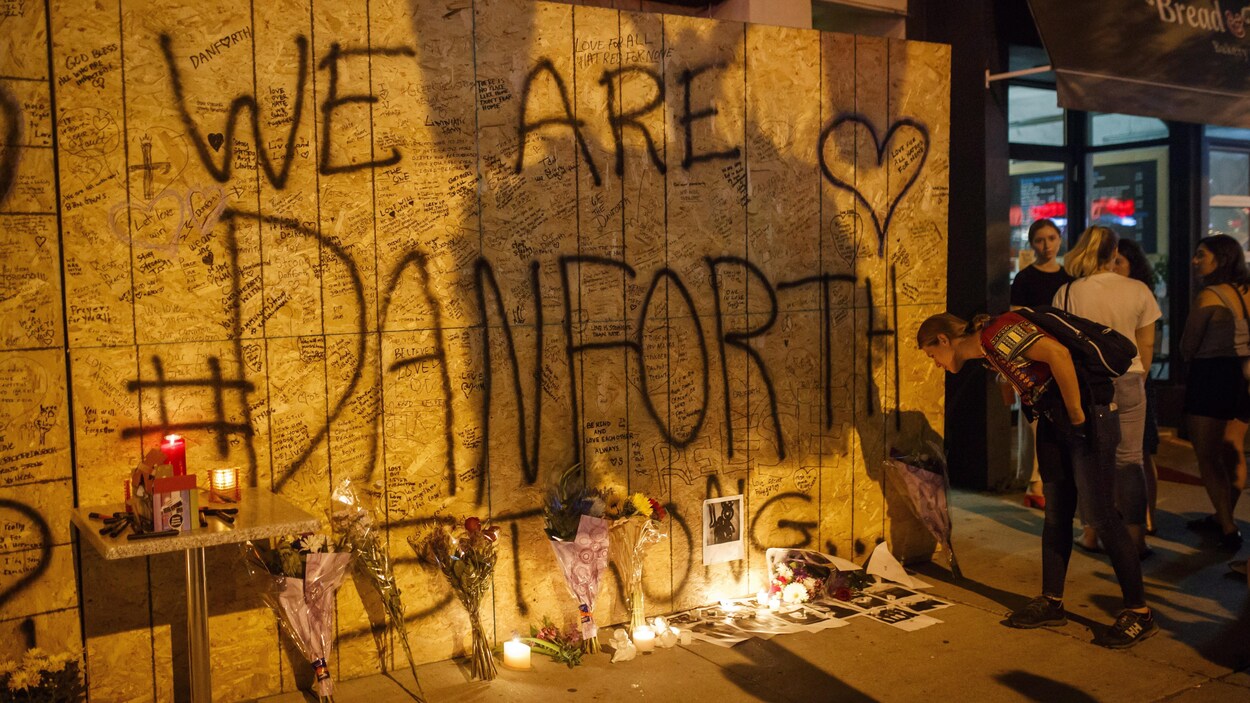 Des gens lisent des messages laissés sur la façade placardée d’un immeuble en rénovation à la mémoire des victimes de la fusillade survenue dimanche soir, sur l’avenue Danforth, à Toronto.