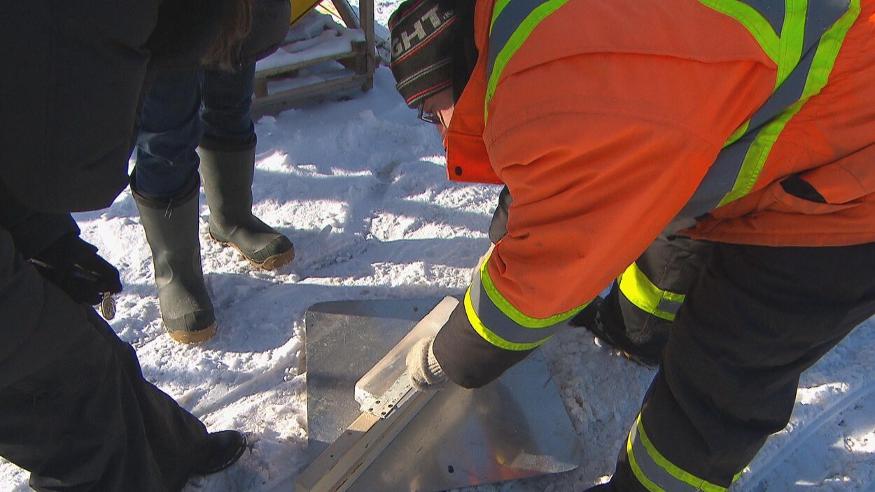 Des bénévoles mesurent l'épaisseur de la glace avec une règle.