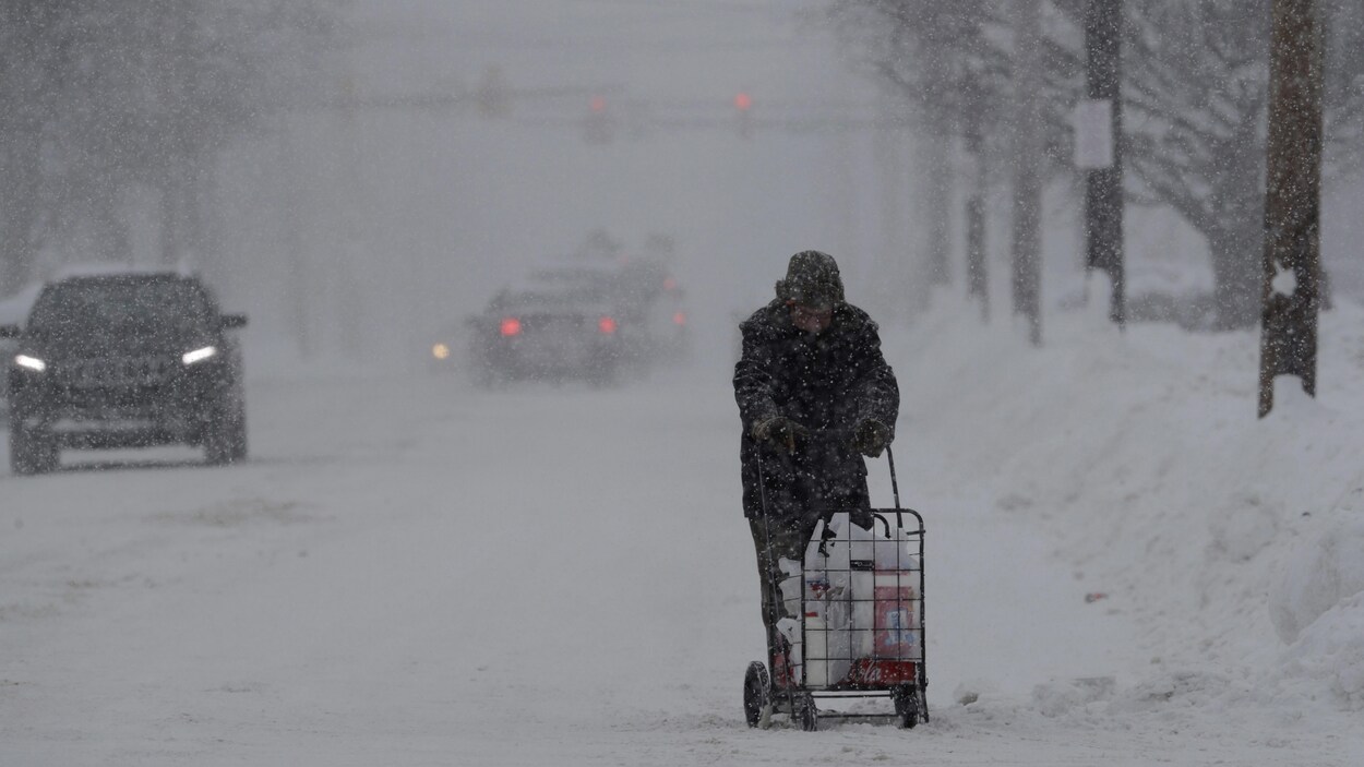 Un homme marche sous la neige avec ses provisions. Un homme marche sous la neige avec ses provisions.