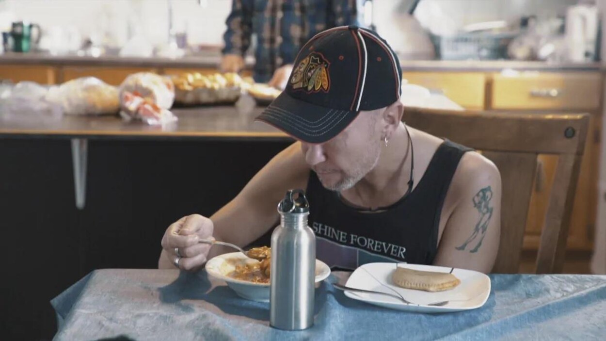 Un homme assis à une table qui mange un bol de céréales.