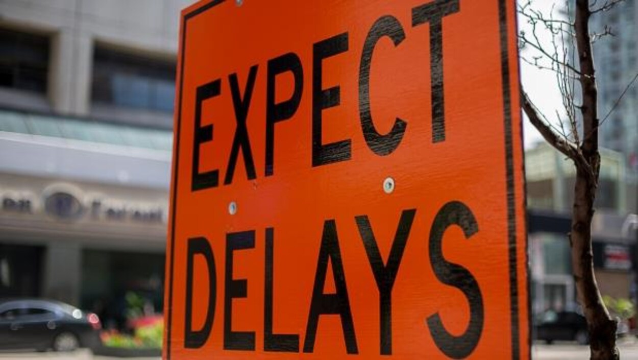 Une pancarte orange sur laquelle est écrit en anglais « Attendez-vous à des retards » afin de prévenir les passagers des éventuels retards de transport dans la ville.
