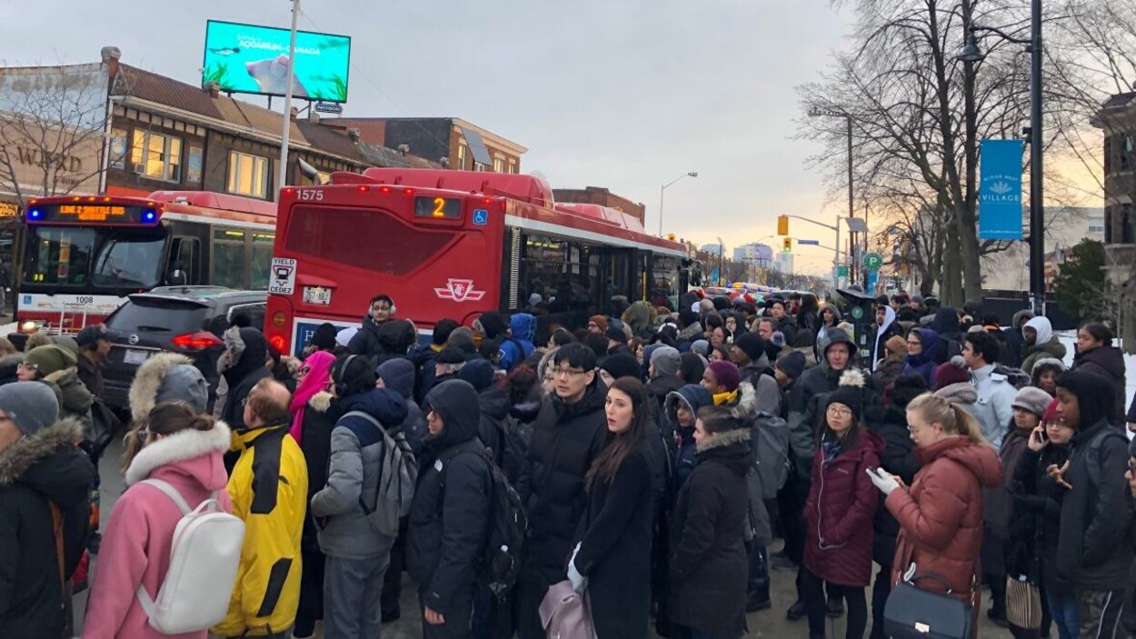 Des dizaines de personnes sur le trottoir près d'un autobus.