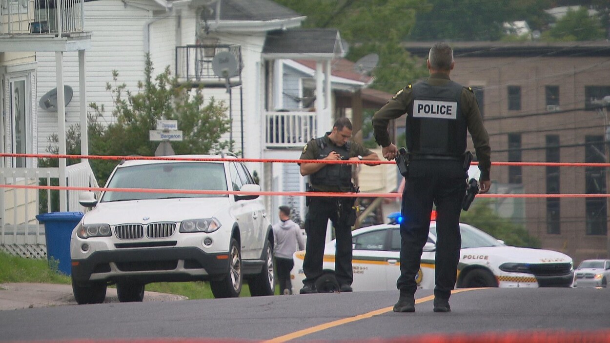Deux policiers surveillent le périmètre de sécurité dans une rue d'Alma.