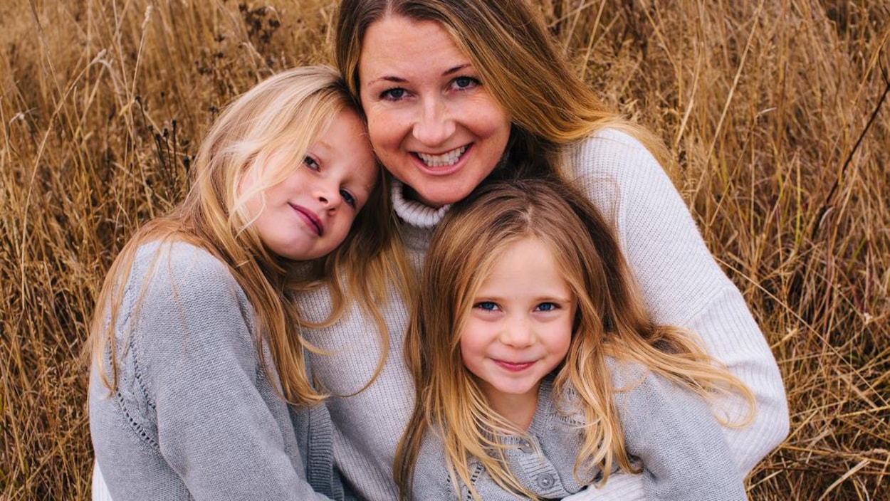 Photo avec une mère et deux jeunes filles souriantes avec des cheveux blonds.