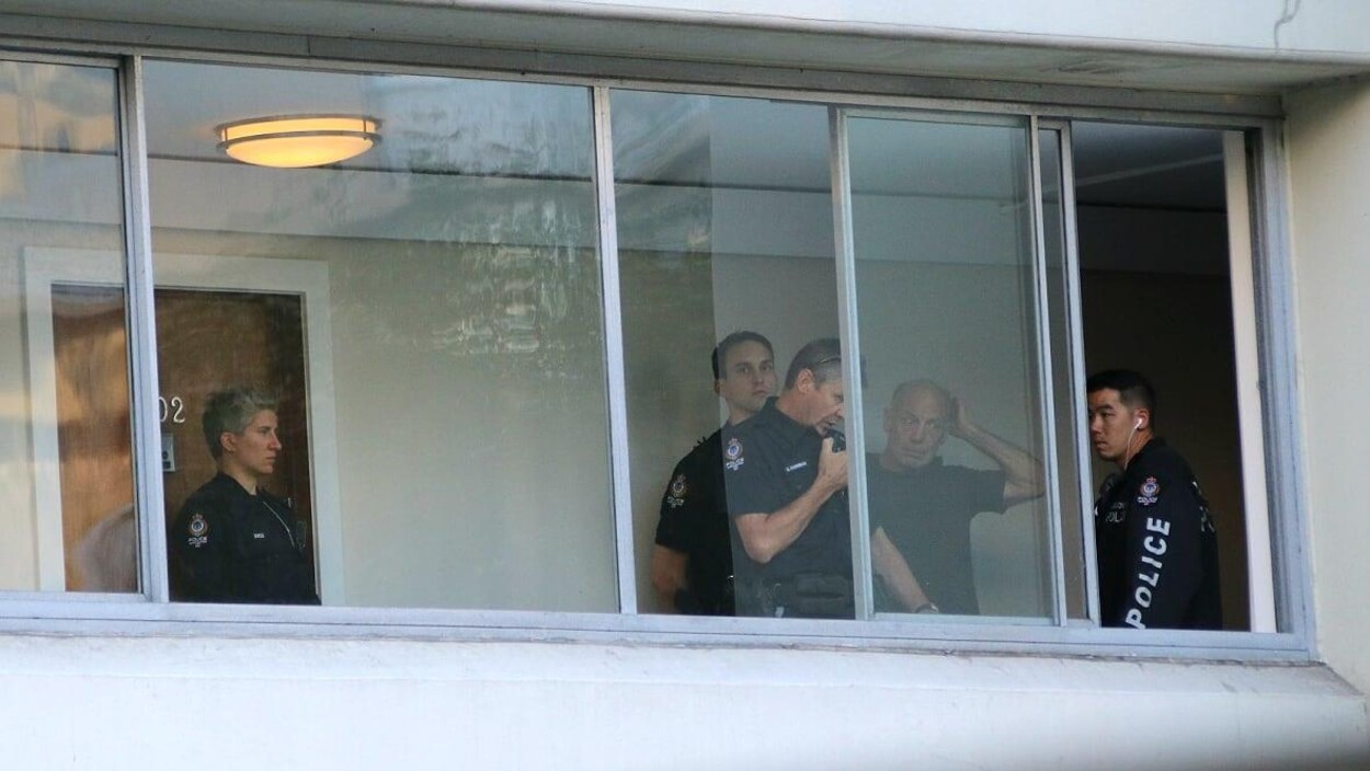 Des policiers discutent derrière une fenêtre.
