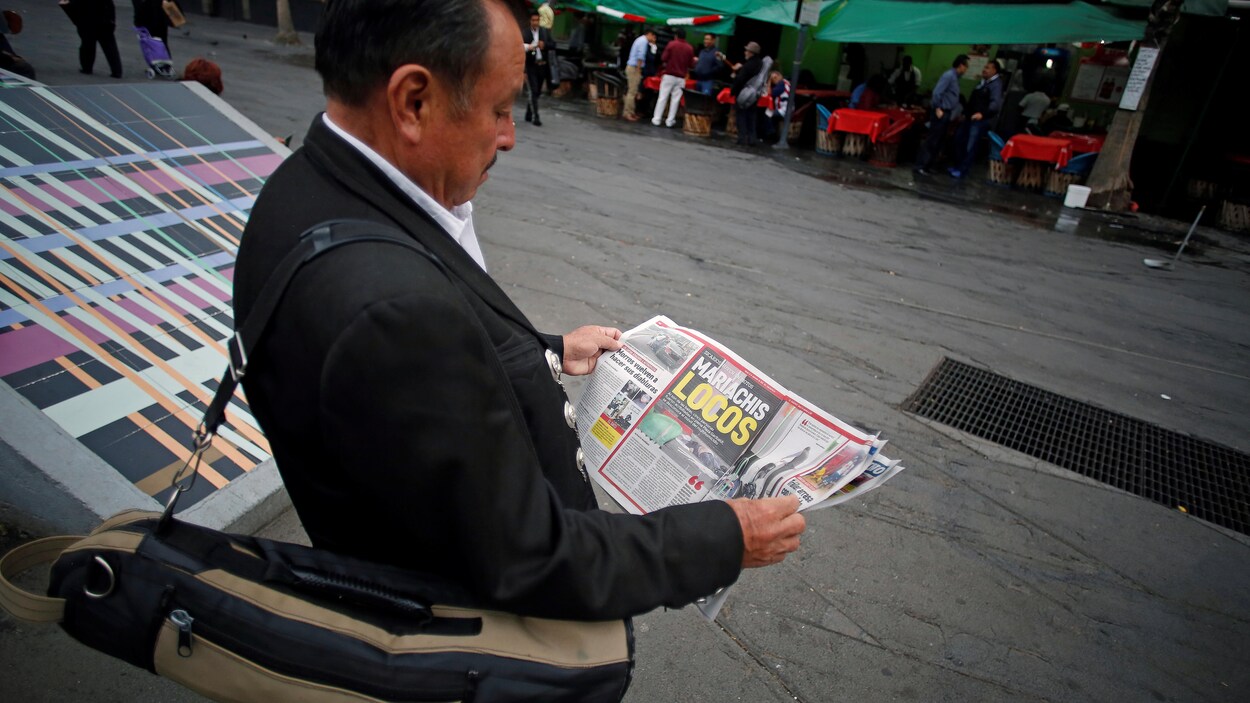 Un mariachi lit un journal dans une rue. Un mariachi lit un journal dans une rue.
