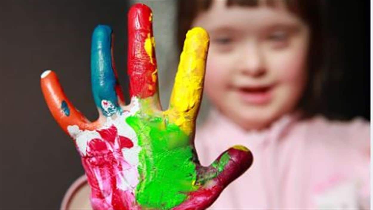 Une enfant joue avec de la peinture.