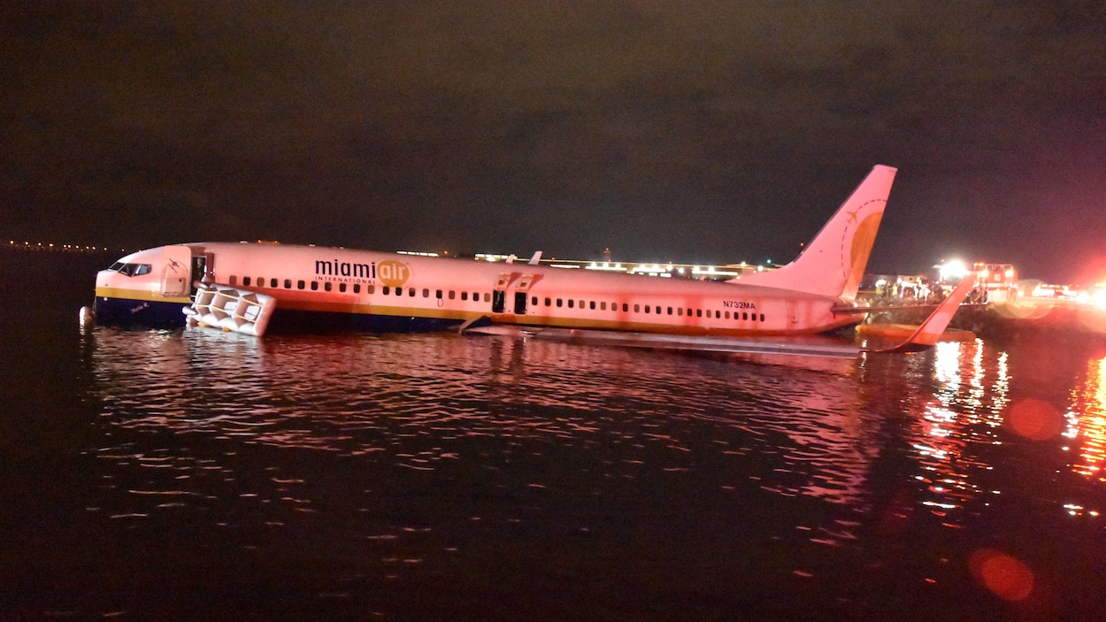 Un avion est posé dans un fleuve en pleine nuit.