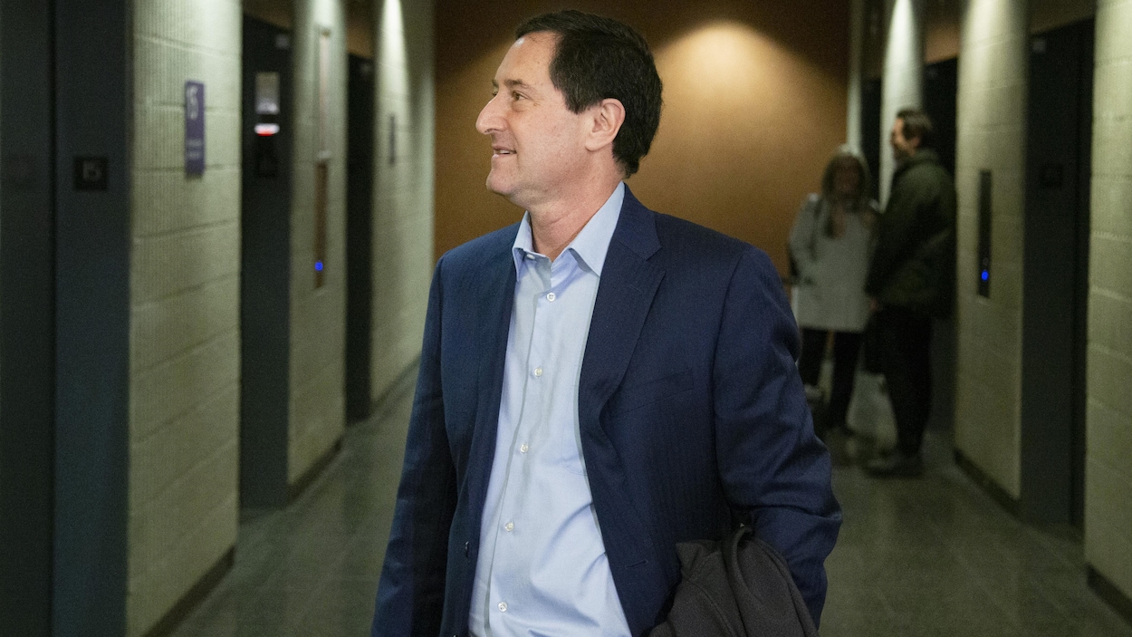 Michael Applebaum photographié de profil sourit dans un couloir.
