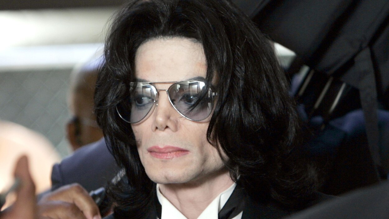 Le chanteur Michael Jackson, vêtu d'un complet noir et portant des verres fumés.