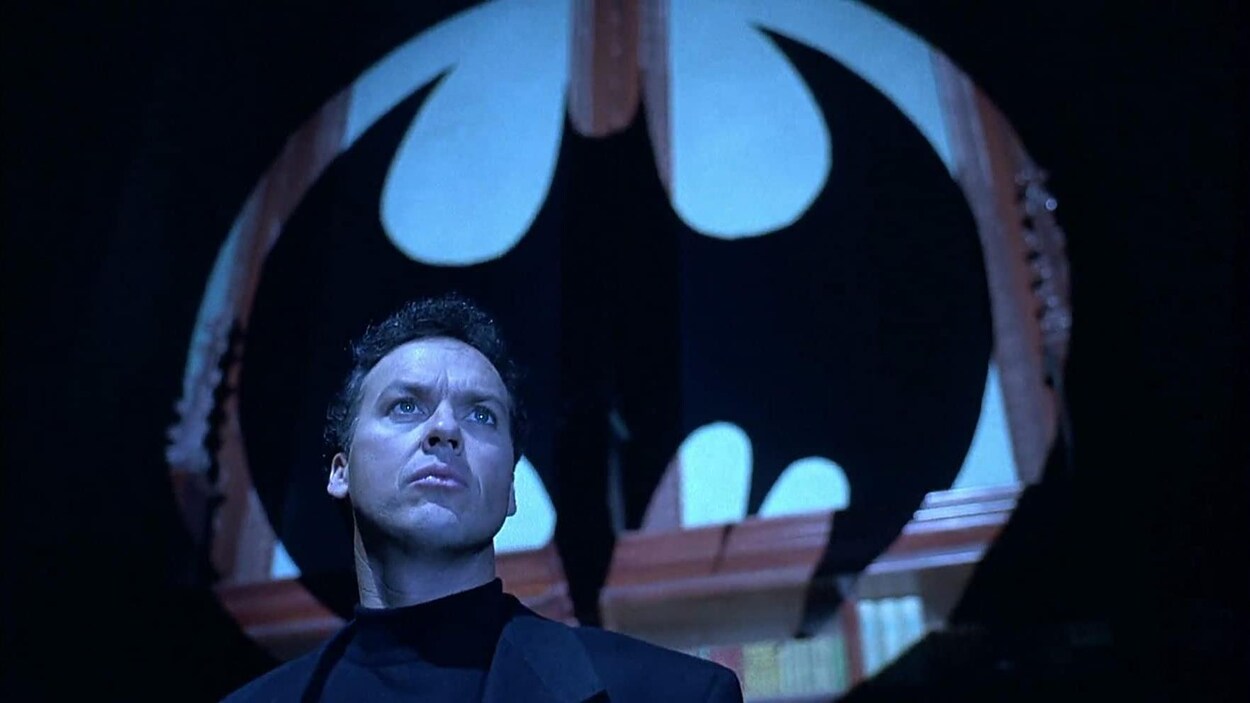 L'acteur regarde au loin avec l'ombre de Batman derrière lui.