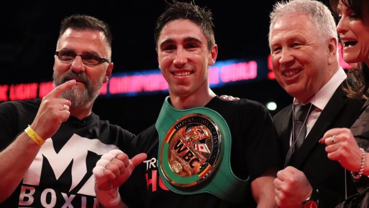 Il porte sa ceinture de champion sur son torse.