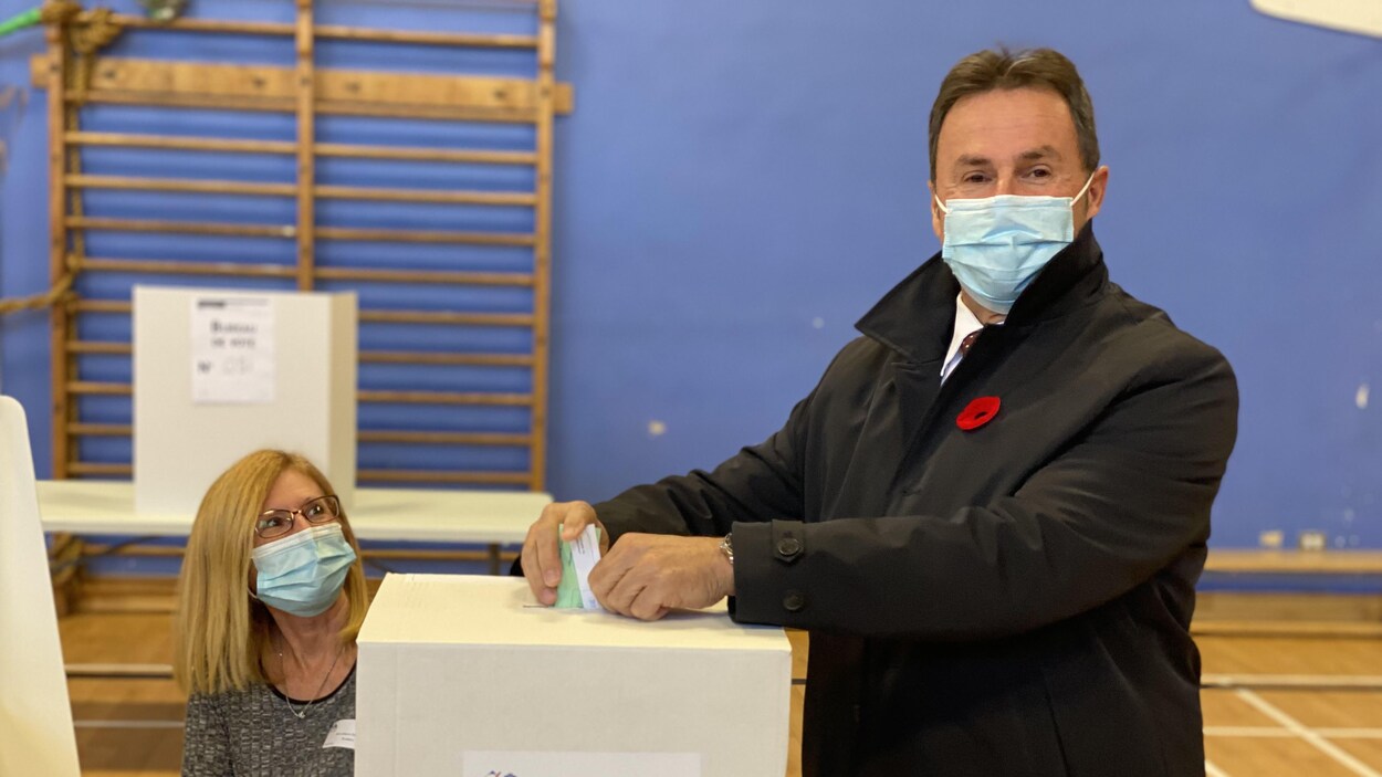 Michel Angers prend la pose devant une boite dans un bureau de vote de Shawinigan.