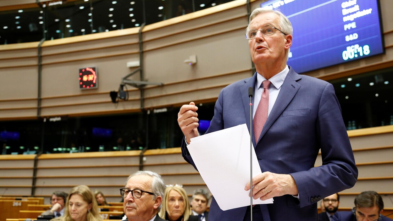 Un homme parle debout dans une grande salle.