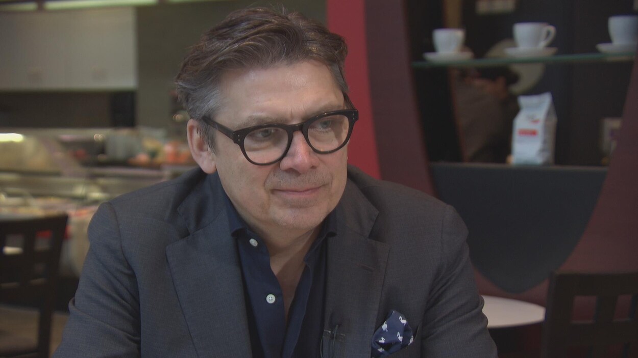 Arborant des lunettes, l'auteur est assis dans un café. Arborant des lunettes, l'auteur est assis dans un café.