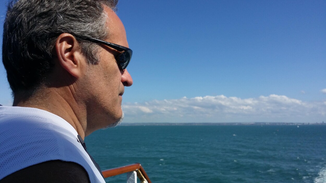 Portrait de profil de l'auteur Michel Pruneau au bord de l'eau.
