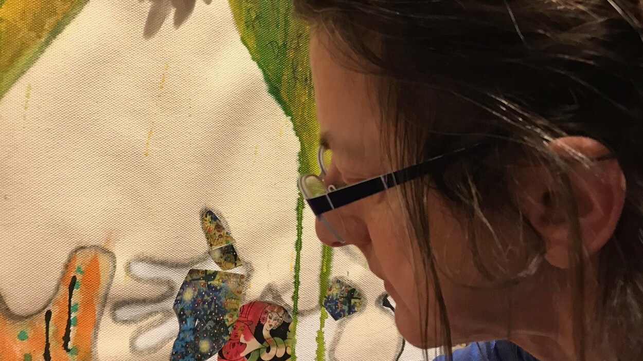 Micheline Plante est penchée sur un pot de peinture, proche d'une toile.