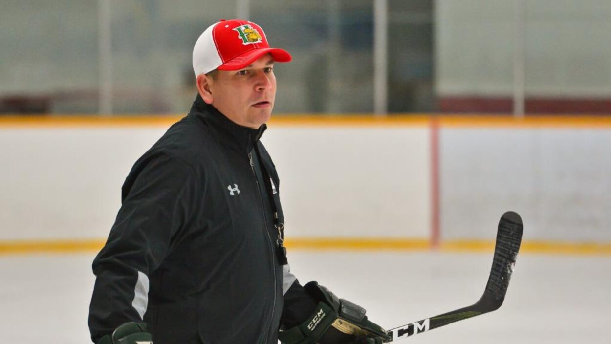 Jim Midgley bâton de hockey en main patine dans un aréna