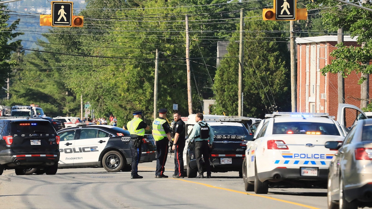 Plusieurs voitures de police cernent un pâté de maisons.