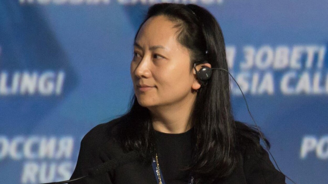 Meng Wanzhou porte une oreillette et regarde vers sa droite.