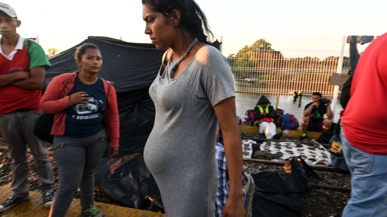 Une Hondurienne enceinte marche parmi d'autres migrants près de la frontière mexicaine.