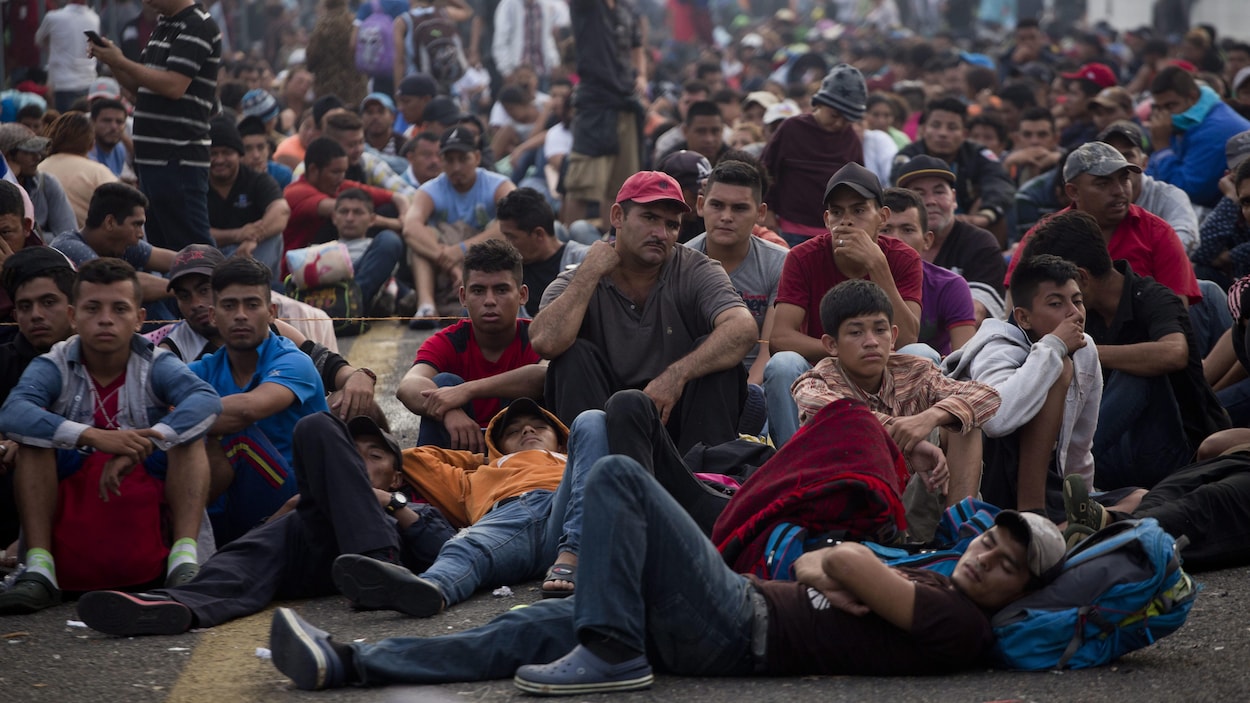Des migrants honduriens assis sur le pont qui sépare le Mexique du Guatemala