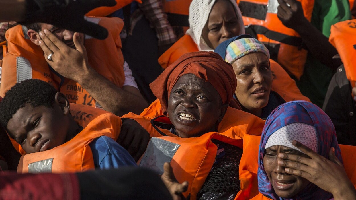 Des femmes migrantes avec des gilets de sauvetage entassées dans un bateau.