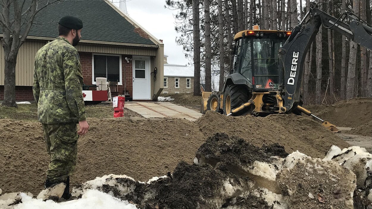 Un soldat canadien supervise des travaux près d'une résidence.