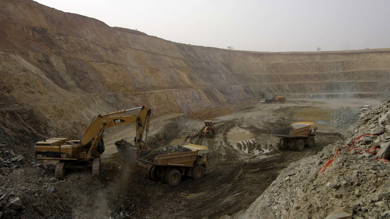 Une grue dispose du minerai dans d'immenses camions de chargement.